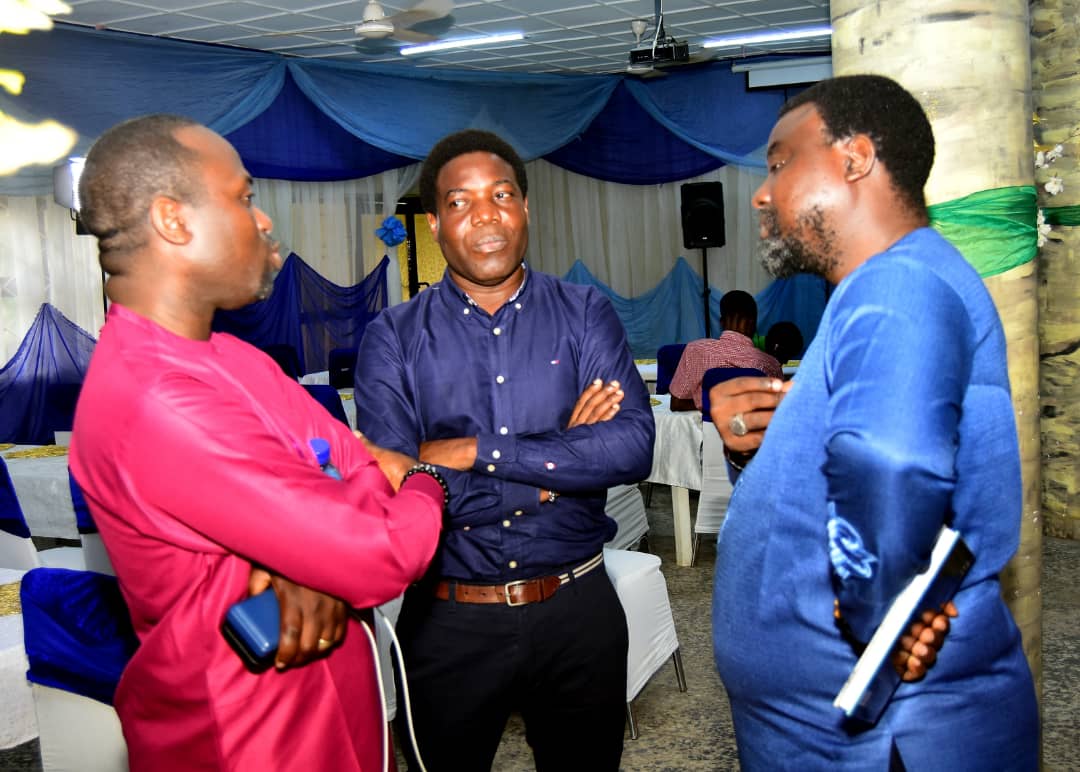 Three men continuing a conversation inside the gathering venue